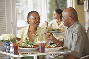 Hombre y mujer sentados en un restaurante comiendo ensaladas.