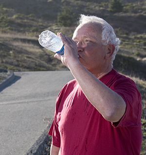 Hombre bebiendo agua al aire libre.