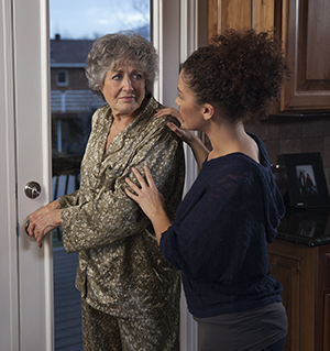 Mujer que previene que una mujer mayor salga hacia afuera por la puerta de la cocina.